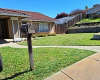 A green yard, with a concrete wall in the background, and a mailbox in the foreground